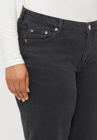 Svarte denimjeans med høy midje, femlommersdesign og detaljer i kobberfarge. Teksturen er jevn med en lett stretcheffekt.