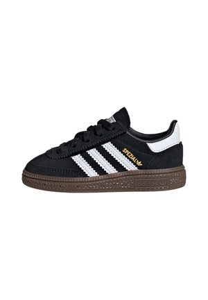 Czarny sneaker Adidas Spezial z białymi paskami, brązową teksturowaną podeszwą i białą pętelką na pięcie, pokazany z profilu bocznego.
