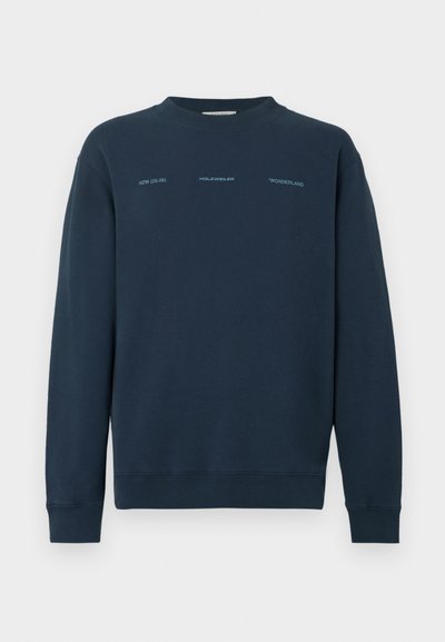 Temno modra jopica z okroglim izrezom, dolgimi rokavi in mehko teksturo. Na sprednji strani ima potiskan napis v kontrastni svetli barvi.