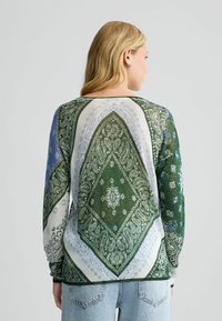 Langsleeve top in een groen en blauw paisleypatroon met ronde halslijn en ribgebreide boorden, met verfijnde details en een zachte textuur.