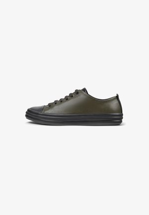 Olivgrüner Sneaker mit einem glatten Lederoberteil, runder schwarzer Gummispitze und strukturiertem schwarzem Profil. Verfügt über schwarze Schnürsenkel und Ösen.
