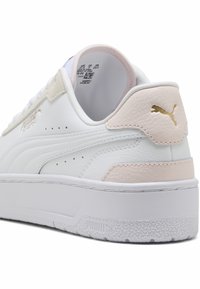 Valkoinen nahkalenkkari vaaleanpunaisilla ja beigen sävyillä, jossa on teksturoitu kanta, rei'itetty muotoilu ja kultainen Puma-logo. Sujuva pinta.