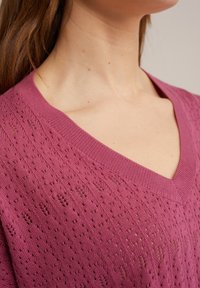 Svetr s výstřihem do V a krátkými rukávy v tmavě růžové barvě, s texturovaným, otevřeným pleteným vzorem, s žebrovaným límcem a lemem.