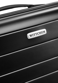 Valise rigide noire avec un design texturé et en relief, ornée du logo argenté 'WITTCHEN'. Elle possède une poignée robuste et des accents brillants.
