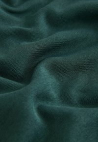Dark green, soft-textured fabric with a smooth finish, featuring slight waves and a subtle sheen, highlighting its stretchy, lightweight quality.