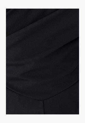 Crni materijal s teksturiranim završetkom, s naborima tkanine koji stvaraju dinamične linije i glatke prijelaze u obliku i dubini.