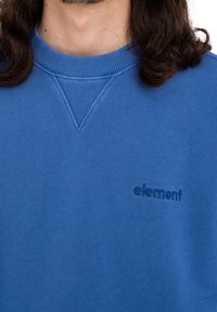 Felpa blu in tessuto morbido, con collo a girocollo rigato e un piccolo logo ricamato dello stesso colore.