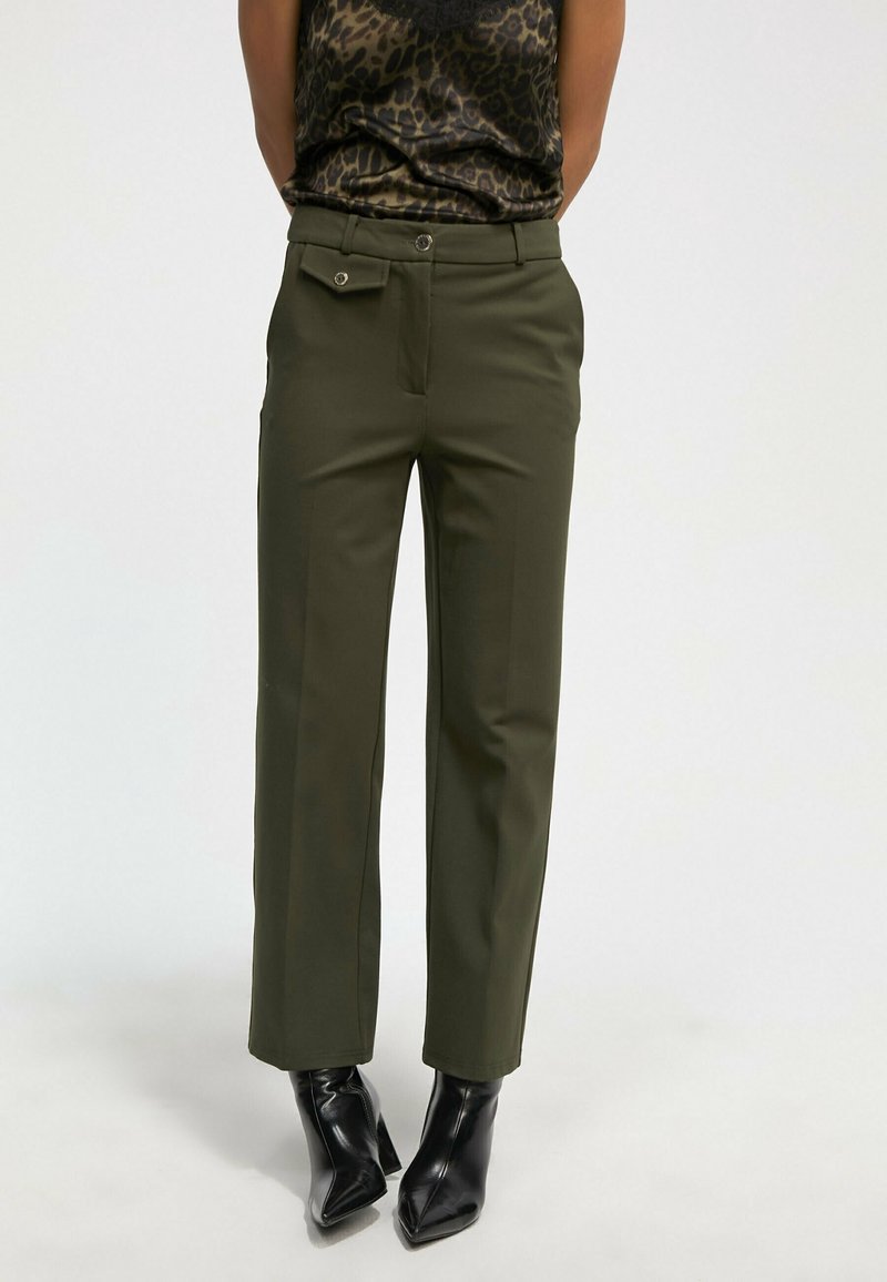 Pantalones verde oliva con un corte ajustado, que presentan un frente plano, dos bolsillos laterales y un detalle de botón de metal en la cintura.