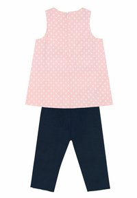 Top sin mangas rosa con lunares blancos, que cuenta con un cierre en la parte de atrás, combinado con leggings azul marino. Material de algodón con una textura suave.