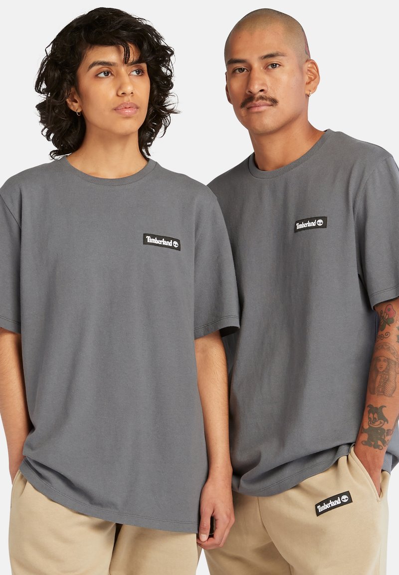 T-shirt grigie in cotone con maniche corte e scollatura rotonda, con un'applicazione del logo nero Timberland sul petto.