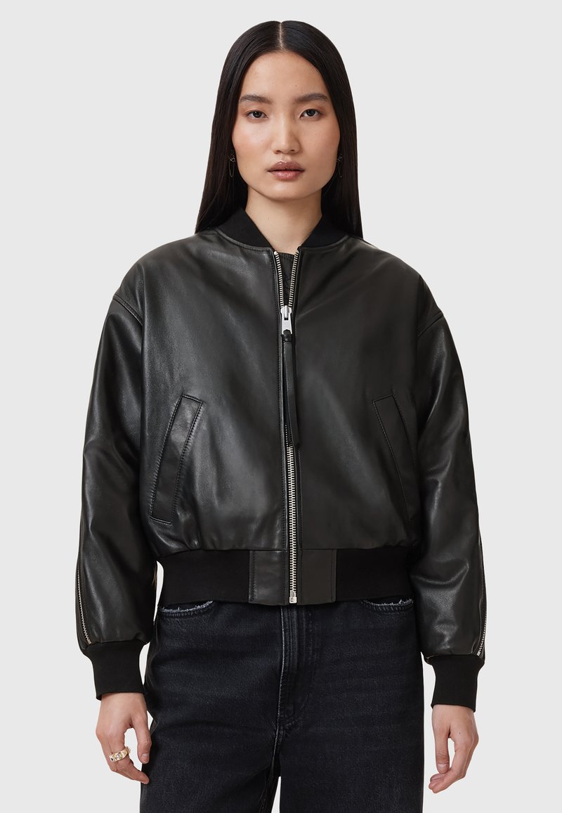 Giacca bomber nera in pelle con chiusura con zip, polsini e orlo a costine, e tasche laterali. Tessuto liscio con una vestibilità rilassata.
