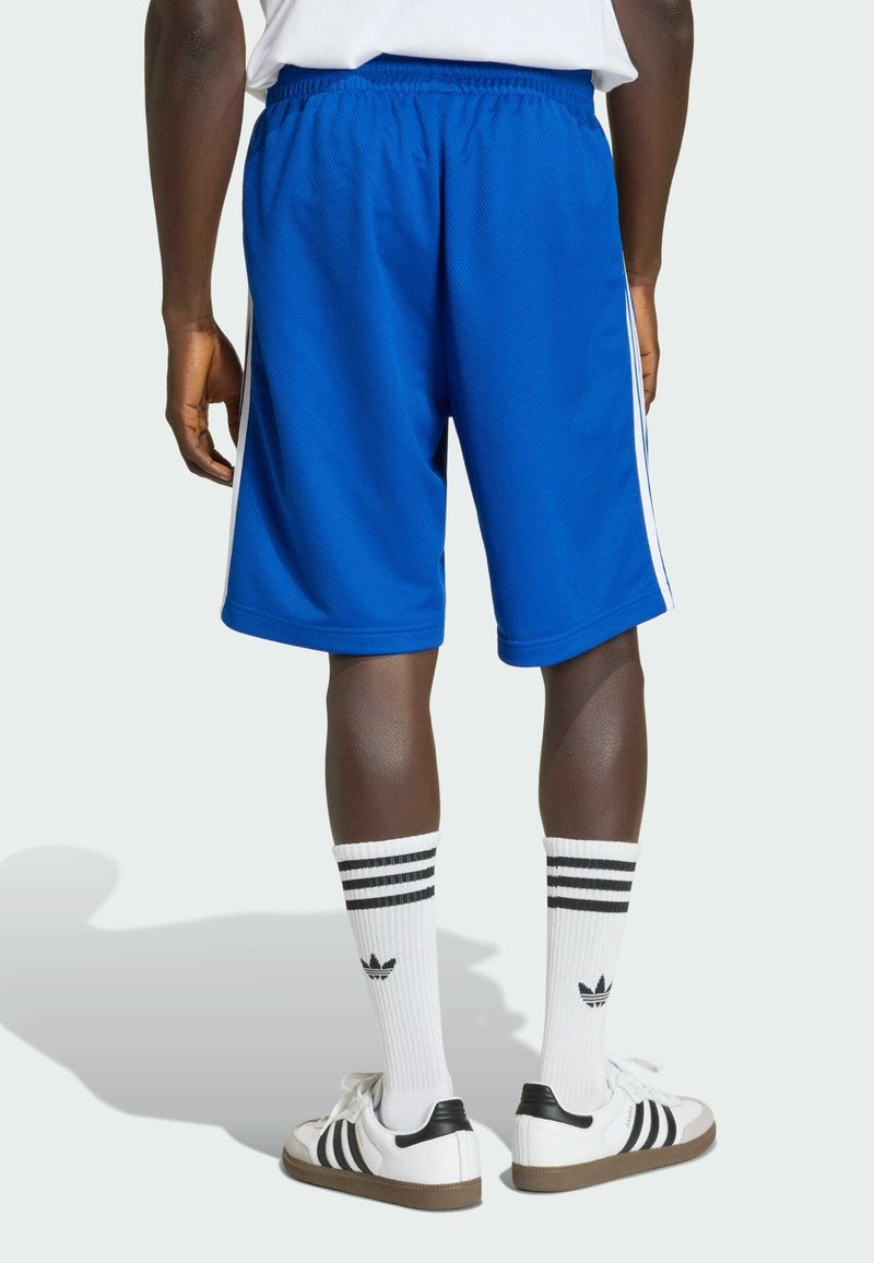 Shorts de sport bleus avec une taille élastique, bandes latérales, texture douce, accompagnés de chaussettes blanches avec des rayures noires et un logo, et de baskets blanches.