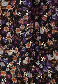 Tissu noir avec un motif floral en violet, orange et blanc, orné de paillettes dorées de différentes formes et tailles.