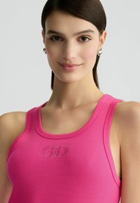 Rosa gerippter Tanktop mit rundem Ausschnitt und Logo-Stickerei. Glatte Textur mit enganliegendem Design. Minimalistische Gestaltung.