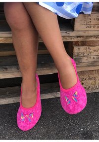 Felle roze instapschoenen van suede, met vlinderborduursels in kleurrijke accenten. Glad oppervlak en afgeronde teenontwerp.