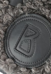 Toppa in pelle nera con design in rilievo, dettagli cuciti e uno sfondo in pelliccia grigia testurizzata caratterizzato da fibre ricci.