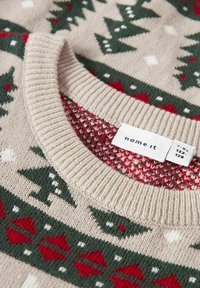 Beżowy sweter dziany z okrągłym dekoltem, zdobiony zielonymi drzewami, czerwonymi diamentami i białymi płatkami śniegu w wzorzysty design. Metka widoczna wewnątrz.