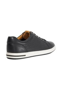 Black leather sneaker featuring a woven texture, white sole with black accents, and brown leather interior. Low-top design with laces.