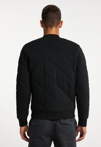 Sweatshirt negru matlasat cu guler rotund și manșete ribalite, având un model cu diamante și o textură netedă.