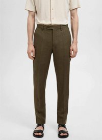 Olijfgroene, op maat gemaakte broek van een gladde, textuurstof. Heeft een rechte pasvorm en zichtbare zijzakken, gecombineerd met zwarte slidesandalen.