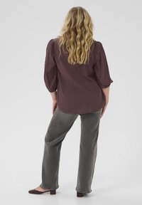 Burgundy blouse with puff sleeves, textured fabric, and subtle pattern, paired with gray wide-leg pants and heeled shoes.