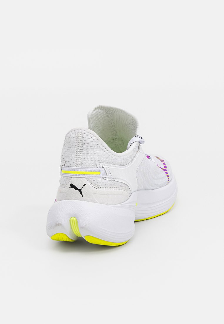 Chaussure de sport blanche avec tige texturée, accents violets et roses, détails réfléchissants et semelle extérieure jaune pour une meilleure adhérence.