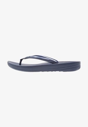 Dark blue flip-flop featuring a textured strap, flat sole, and a minimalist design. The outsole shows a patterned tread for traction.