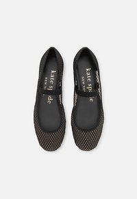 Bailarinas de malla negras con punta redondeada y una correa elástica negra incorporada. El interior presenta la marca "kate spade" en dorado sobre un fondo negro.