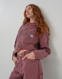 Giacca cropped a righe rosse e blu con bottoni frontali e tasca a toppa, abbinata a pantaloni a vita alta coordinati con tasche frontali.