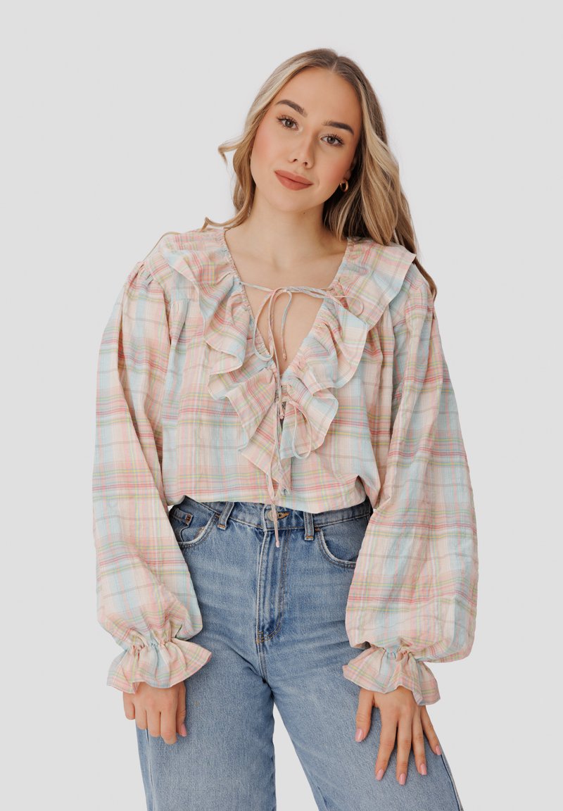 Blusa de cuadros ligera en colores pastel, con un cuello y mangas con volantes, cierre con lazo y mangas globo voluminosas.