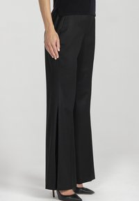 Czarne spodnie o szerokich nogawkach z przednimi rozcięciami, gładka tkanina, dopasowany krój i wysoki stan. Połączone z czarnymi szpilkami na spiczastym nosku.