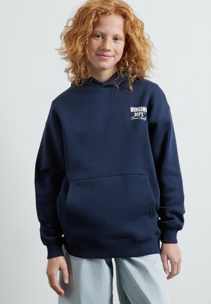 Hoodie bleu marine avec une poche frontale, texture douce et logo blanc sur la poitrine gauche. Présente une capuche avec cordon de serrage et des poignets côtelés.