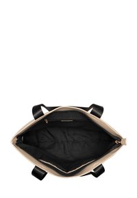 Beige schoudertas met zwarte binnenkant, voorzien van dubbele zwarte handvatten. De binnenkant bevat vakken en een ritssluiting. Soepele textuur.