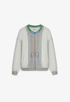 Veste gris clair à fermeture éclair avec un panneau central gris plus foncé, manches crème, col vert et bleu, et cordons jaunes ornés de perles pastel.