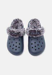 Kék slip-on klumpák szellőzőnyílásokkal és szürke bolyhos béléssel és pánttal, felülről látható fehér háttérrel.