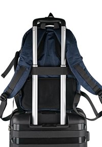 Mochila azul marino con respaldo de malla negra, correas ajustables y mango retráctil de aluminio, acoplada a una maleta rígida negra con ruedas.