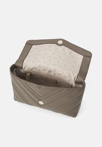 Sac à main matelassé vert olive, en cuir lisse. Doté de ferrures dorées et d'un intérieur avec motif logo DKNY. Fermeture à pression magnétique.