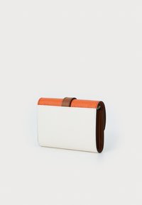 Läderplånbok med en texturerad orange övre del, slät vit kropp och ett brun remkläpp. Kompakt rektangulär form.