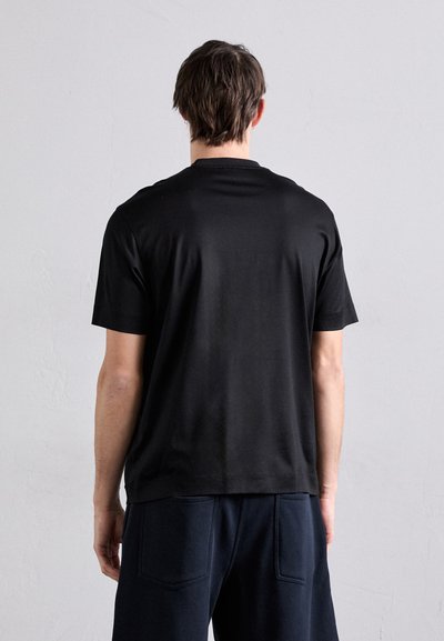 T-shirt noir à manches courtes avec col rond, fabriqué en tissu lisse. Présente une coupe décontractée sans logos ni motifs visibles.