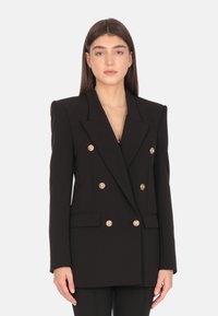 Blazer nero doppiopetto realizzato in tessuto strutturato, con rever a punta e bottoni dorati. Vestibilità su misura, tasche frontali.