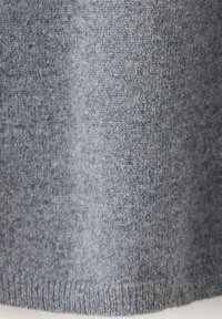 Gros plan d'un tissu tricoté gris doux avec une texture fine et un ourlet côtelé en bas.