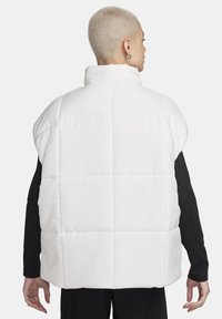 Chaleco acolchado blanco con un alto cuello, diseño acolchado y corte relajado. Presenta una textura suave y sin hardware ni acentos visibles.