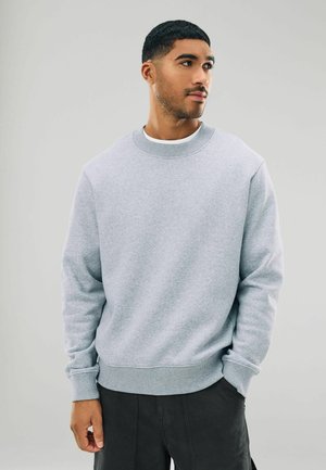 Light gray sweatshirt made of cotton blend fabric. Features a round neck, ribbed cuffs, and a straight hem. No visible patterns or logos.