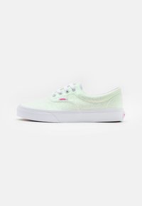 Valkoiset tennarit säihkyvällä, tekstuuripinnalla, joissa on nauhakiinnitys, valkoinen kumipohja ja pieni vaaleanpunainen logo.