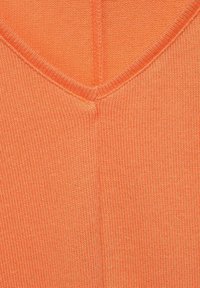 Vêtement en v-neck tricoté de couleur orange vif. Présente une texture avec des coutures visibles et des bords côtelés le long de l'encolure.