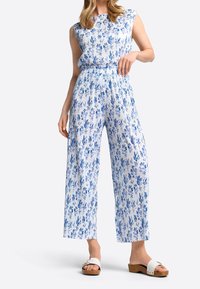 Blauwe en witte jumpsuit met bloemenpatroon, wijd uitlopende pijpen en een getailleerde taille, gemaakt van lichtgewicht stof. Het heeft een mouwloos ontwerp en een geribbelde structuur.