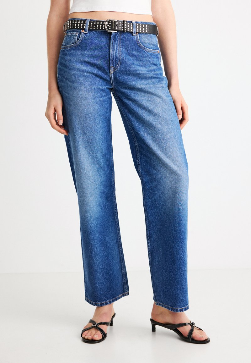 High-waisted blue denim jeans with a straight-leg fit, featuring a black studded belt and visible pockets. Smooth texture, minimal fading.
