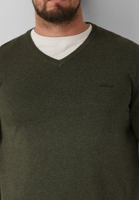 Olivgrüner Strickpullover mit V-Ausschnitt und subtiler Textur. Enthält ein kleines Logo auf der linken Seite der Brust.