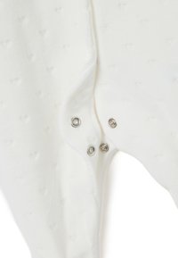 Witte bodysuit met een getextureerd hartpatroon, zachte stof, drukknoopsluitingen aan de zijkant en gladde randen.