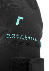 Schwarzer Softshell-Stoff mit türkisfarbenem Text, der "SOFTSHELL" und "4 WAY STRETCH" liest, mit strukturierter Oberfläche und Klettverschlussakzenten.